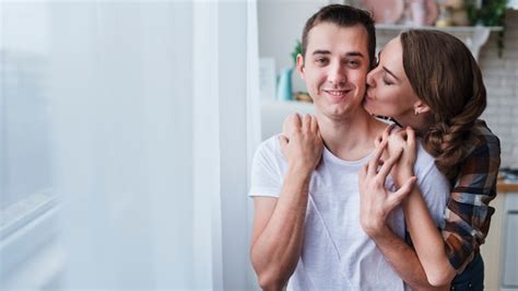 free photo positive couple hugging and kissing near window