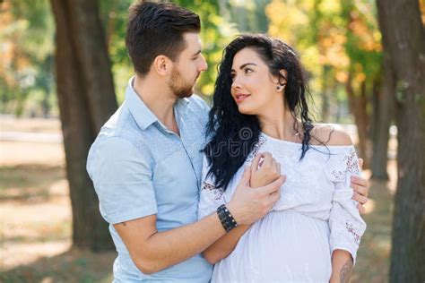 Pregnant Girl Walks In The Park With Her Husband Hugging And Kissing Enjoying The Beautiful