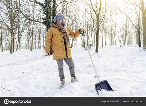 Young Man Shoveling Snow Near A Small Wood — Stock Photo