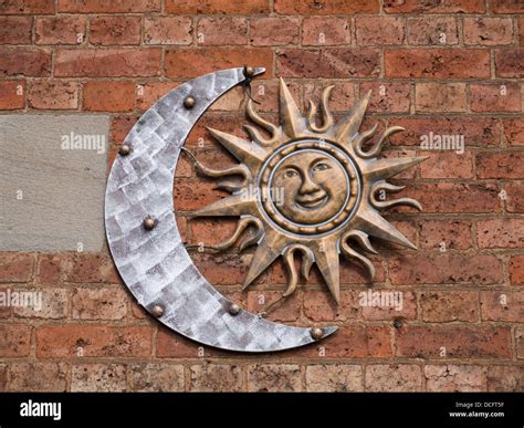 Copper Sign Of A Moon And Smiling Sun Hanging On A Red Brick Wall Stock