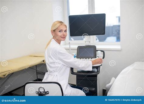 Blond Pretty Ultrasound Specialist In White Robe Sitting At The