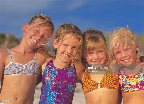 Portrait Of Four Young Girl Wearing Swimsuits And Smiling On The Beach