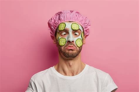Free Photo Young Man Crosses Eyes Applies Cream Mask On Face With