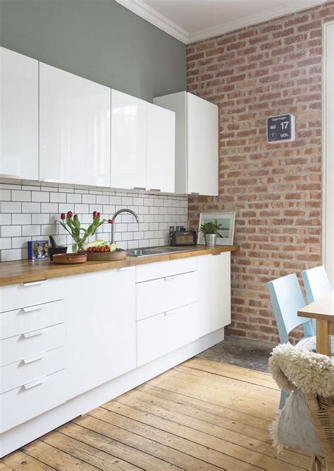 White metro tiles cover the backsplash. White gloss kitchen units by Ikea, Brick Slip Wall. Fired ...