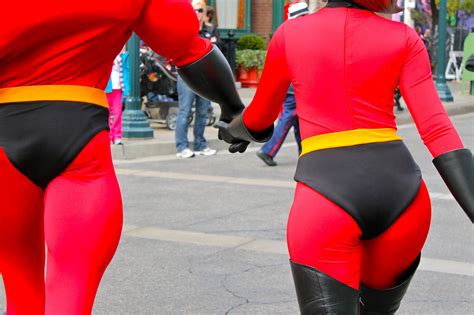Two People In Red And Black Costumes Walking Down The Street With One Person Dressed As An Antman