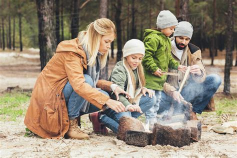 Mother And Daughter Warming Hands With Bonfire While Father And Son