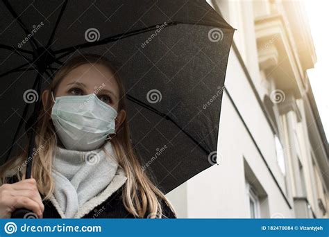 A Girl In An Antiviral Mask Is Walking Down The Street Stock Photo