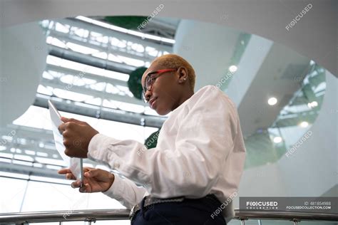 black female clerk in glasses browsing digital tablet during work in
