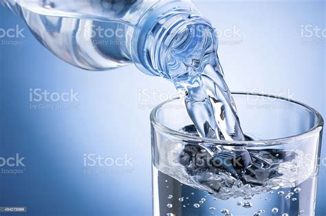 Wasser Aus Der Flasche Ins Glas Auf Blauem Hintergrund Gießen Stockfoto