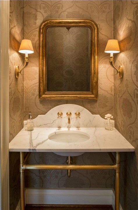 A Bathroom With A Marble Counter Top And Gold Framed Mirror Above The