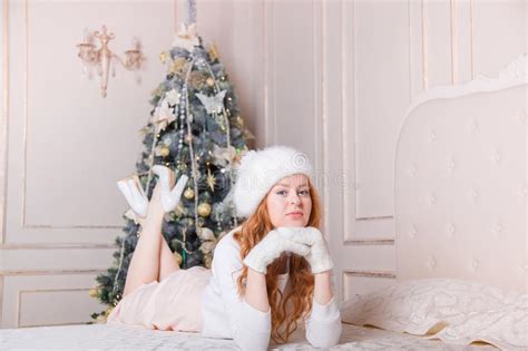 Happy Redhead Woman With An Ornament Lying Beside A Christmas Tree In