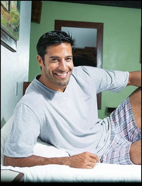 A Man Sitting On Top Of A Bed Smiling