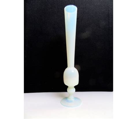 A Tall White Glass Vase Sitting On Top Of A Table