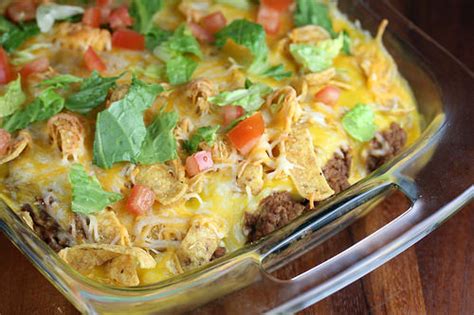 1 pound ground beef 1 onion, diced 1 packet of taco seasoning ½ cup water 1 (14oz) can diced tomatoes (or salsa) 1 cup tomato sauce 1 cup corn 1 bag fritos® corn chips (about 5 cups) 2 cups cheddar cheese, shredded ¼ cup green onions chopped ¼ cup diced fresh. taco casserole with fritos