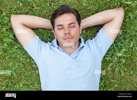 Young Man With Hands Behind Head Lying On Grass Stock Photo Alamy