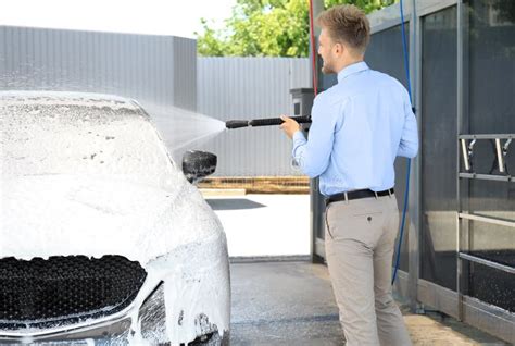 Businessman Cleaning Auto With High Pressure Water Jet At Car Wash