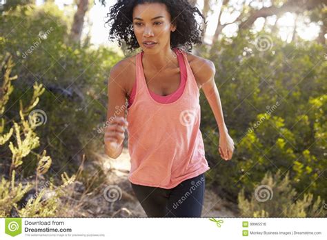 Determined Young Black Woman Jogging In A Forest Close Up Stock Photo