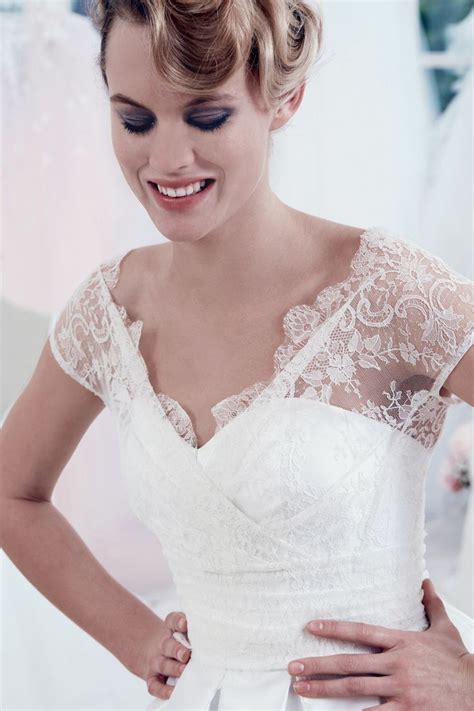 A Woman In A Wedding Dress Is Smiling At The Camera While Holding Her Hands On Her Waist