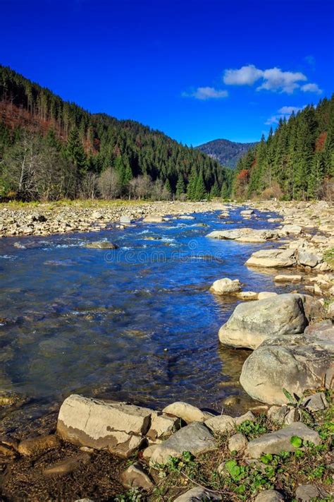 River Flows By Rocky Shore Near The Autumn Mountain Forest Stock Photo