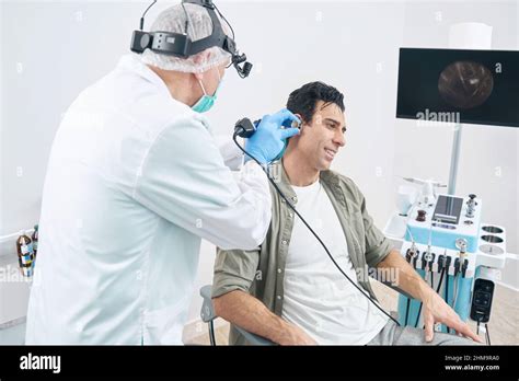 Otorhinolaryngologist Examining Male With Medical Instrument At The