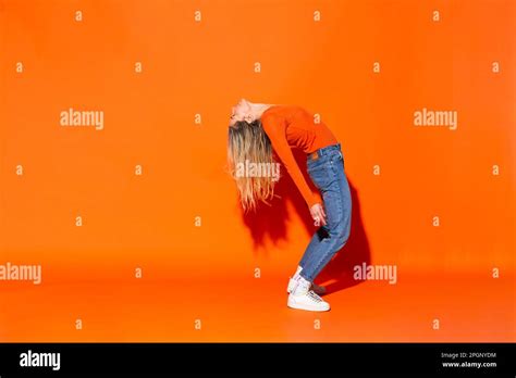 Woman Bending Over Backwards Against Orange Background Stock Photo Alamy