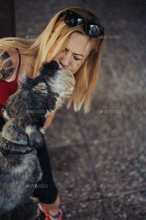 Woman Kissing Her Dog In The Mouth While Having A Good Time Outside