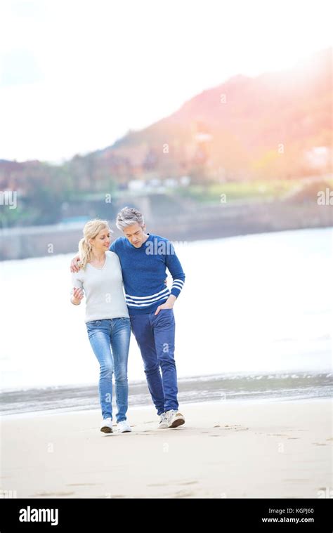 Middle Aged Couple Walking On The Beach Full Length Stock Photo Alamy