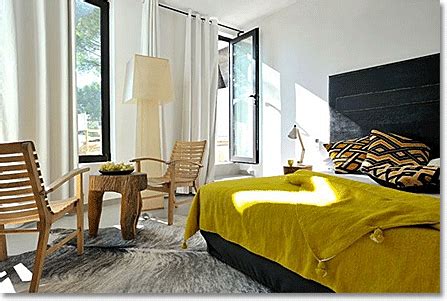 Wicker dining chairs bring a natural element to the space that contrasts with the traditional chandelier but complements the live plants. Yellow Bedroom Color Ideas