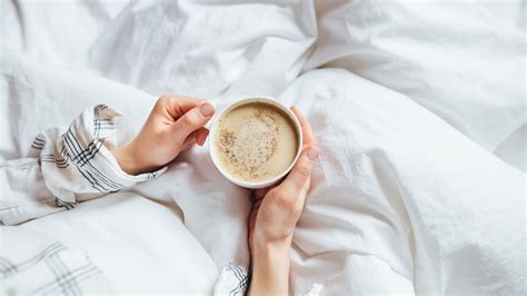 Close Up Of Hands Holding A Cup Of Coffee On The Bed At The Capital