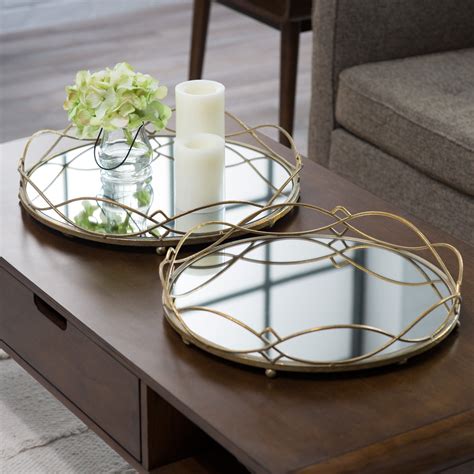Two Round Metal Trays With Candles And Flowers Sit On Top Of A Coffee Table