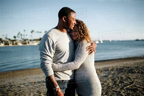 Multi Racial Couple Embrace On Beach At Sunset Stock Photo Dissolve