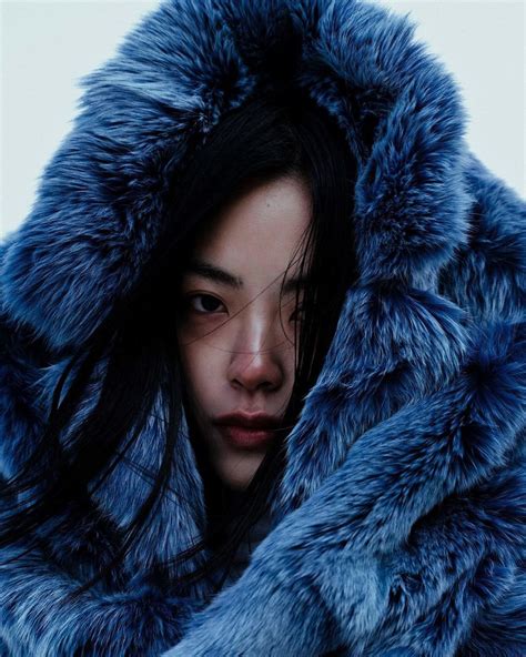 A Woman Wearing A Blue Fur Coat And Looking Off To The Side With Her