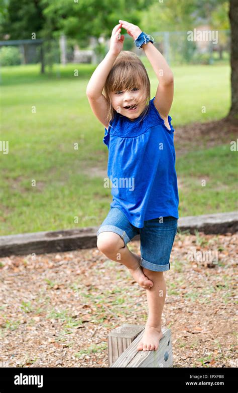 Child Walking On An Outdoor Wooden Balance Beam With A Ballerina Pose