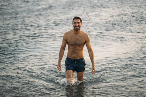 Shirtless Handsome Man Walking In Sea During Sunset Stock Photo