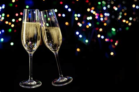 Two Champagne Glasses Toast Against A Dark Background With Colorful Bokeh Lights New Year And