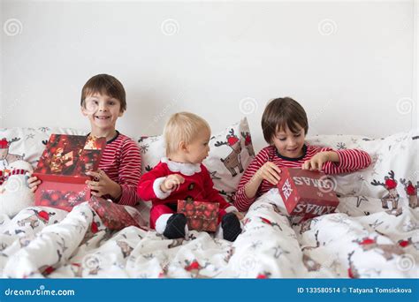 Happy Children Opening Christmas Presents In Bed Stock Photo Image