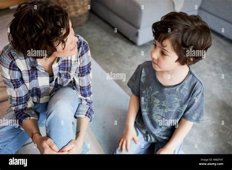Madre E Hijo En Casa Sentado En El Suelo Hablando Fotografía De Stock