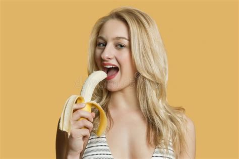 portrait of a beautiful blond woman eating banana over colored background stock image image of