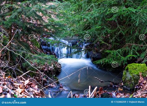 Small Waterfall On A Creek In Winter Paneled With Branches And Grass