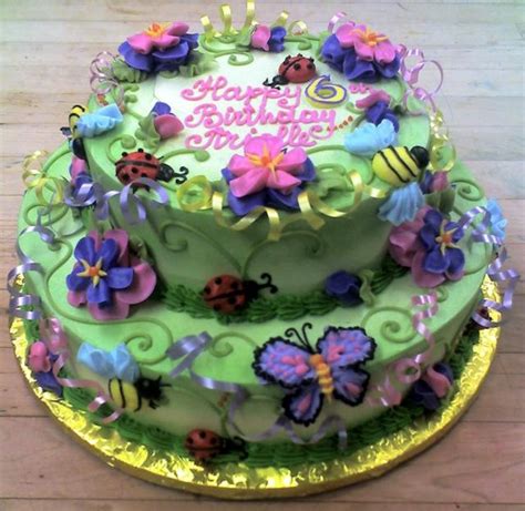 Little kid girl 5 years celebrating her birthday together with friends. 2 tier Green Garden birthday cake with butterflies ...