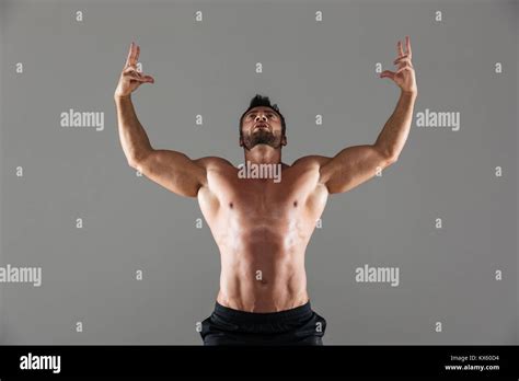 Portrait Of A Confident Strong Shirtless Male Bodybuilder Posing While Standing With Arms Raised