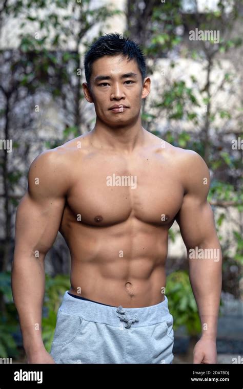 A Muscular Male Japanese Amateur Bodybuilder Poses Outdoors In A Street