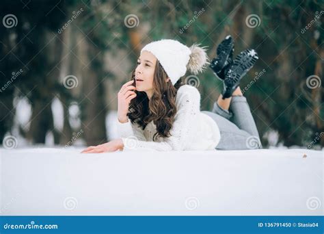 Young Pensive Woman Is Lying On The Snow During The Walk Stock Photo