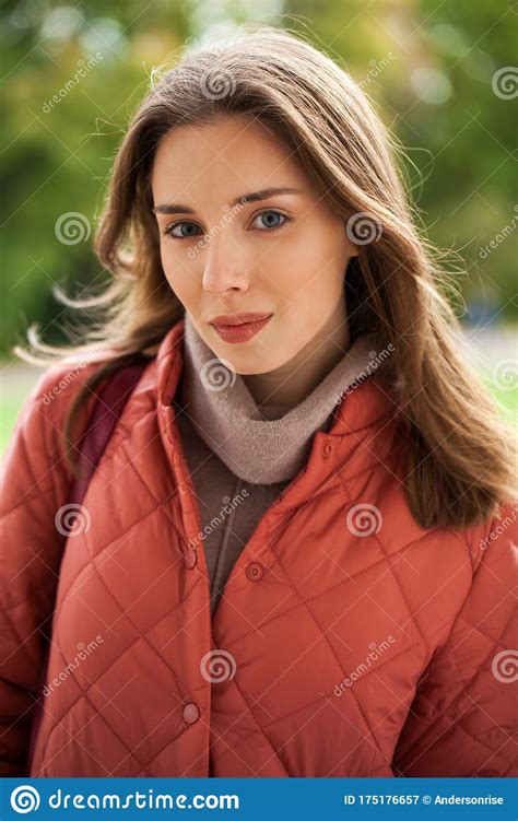 Close Up Portrait Of A Young Beautiful Brunette Girl In Coral Coat
