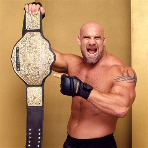 A Man Holding A Wrestling Belt In His Right Hand And Pointing At The Camera With Both Hands
