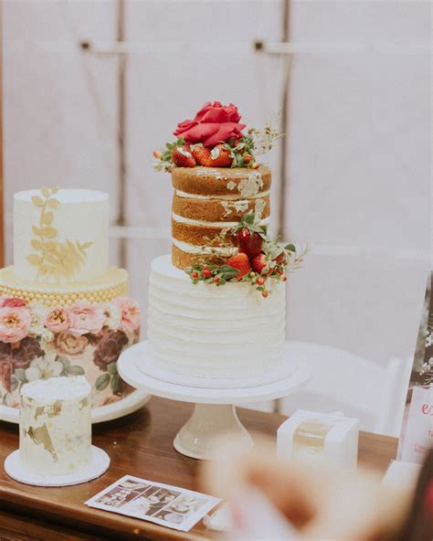 Three Tiered Cake Sitting On Top Of A Wooden Table Next To Other Cakes