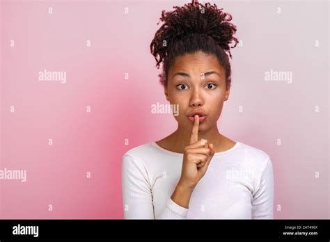 cute mulatto woman shows a silence gesture touching by index finger her lips concept gesture