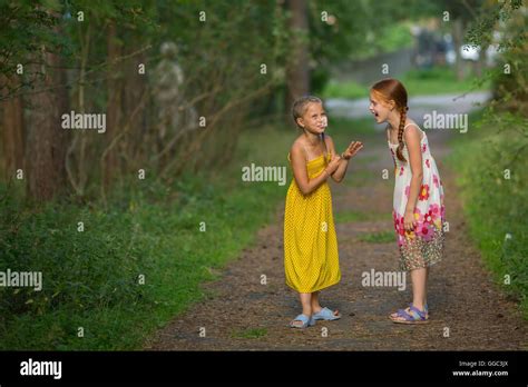 Two Cute Little Girls Talking Animatedly Standing In A Park Stock Photo