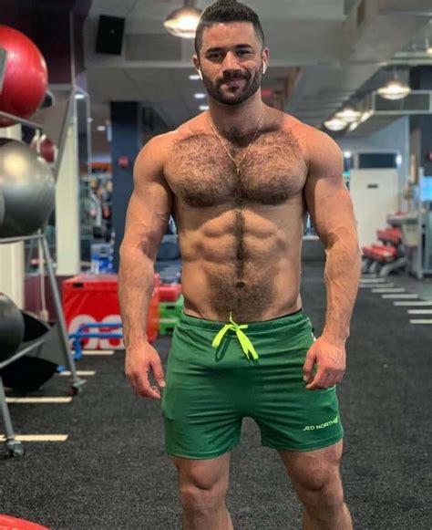 A Shirtless Man Standing In A Gym With No Shirt On And Green Shorts Posing For The Camera