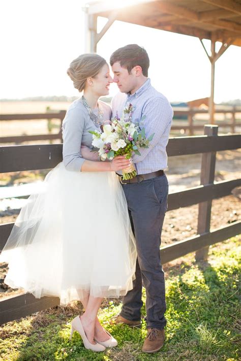 A Man And Woman Standing Next To Each Other Near A Fence With Flowers